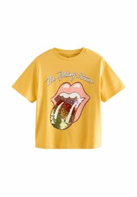 Gelbes Baumwoll-T-Shirt mit einem großen pinken Rolling Stones-Logo und einem mit Pailletten gestalteten Zungenmuster in Rot, Grün und Gold. Kurze Ärmel.
