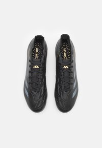 Scarpe da calcio sintetiche nere con un design testurizzato, dotate di accenti blu, colletto imbottito e logo dorato sulla soletta.