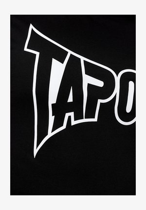 Melna kokvilnas T-krekls ar uzkrītošu balto "TAP" tekstu dinamiskā fontā, kas izvietots izcilā vietā uz krūšu daļas.