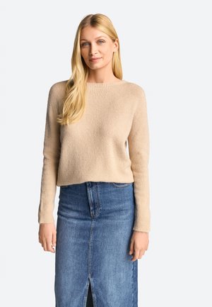 Pullover in maglia beige con maniche lunghe, scollatura rotonda e texture morbida abbinato a una gonna di jeans blu con spacco frontale.