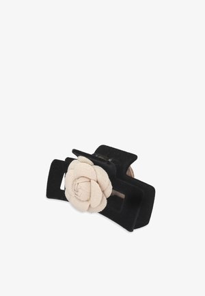 Fermaglio nero con un accento floreale beige texture. Il fermaglio presenta una forma rettangolare e una finitura opaca e morbida.