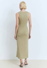 Knit, sleeveless olive green midi dress with a fitted silhouette, featuring a round neckline and smooth texture. Worn with strappy heeled sandals.