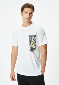 Biała bawełniana koszulka z grafiką "Rick and Morty" na lewej piersi, z postaciami z kreskówki i czarno-białym tłem w spirali.