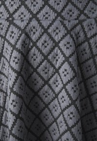 Textil, amelyen sötét háttéren szürke gyémánt mintázat található, texturált felülettel. A dizájn összefonódott négyzetekből és keretekből áll.