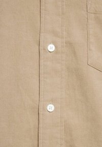 Beige corduroy shirt featuring white buttons, vertical ribbed texture, a chest pocket, and a classic collar design.