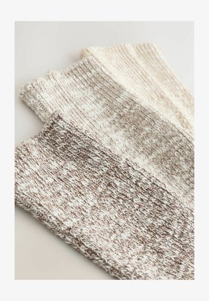 Conjunto de tres calcetines de punto en tonos beige y crema, con un patrón texturizado y puños acanalados para mayor comodidad.