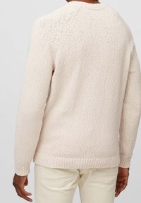 Lichtbeige trui met een gestructureerde breiwijze, ronde halslijn en geribbelde manchetten. Beschikt over naadloze raglanmouwen en een aansluitende zoom.