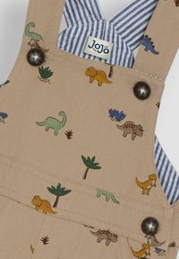 Beige Kinder-Overalls mit verschiedenen bunten Dinosaurier- und Pflanzenmotiven, dunklen Knöpfen und blau-weiß gestreiften Trägern.