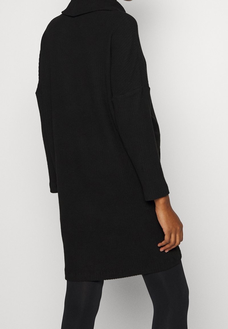 Cardigan noir tricoté avec col, manches longues et poches latérales. Caractérisé par une texture côtelée et une coupe décontractée, arrivant à mi-cuisse.