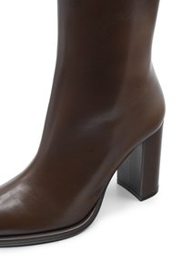 Stivaletto in pelle marrone con finitura liscia, punta affusolata e tacco a blocco. Presenta una silhouette elegante e aderente.