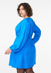 Zila garām piedurknēm kleita ar teksturētu rakstu, pieskaņotu vidukli un izplestu svārku. Audums ir viegls un elpojošs.