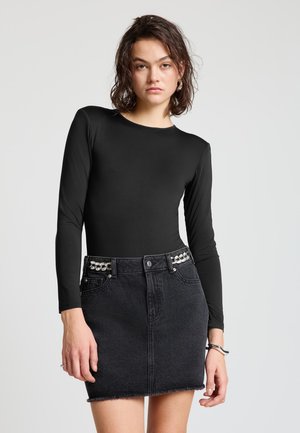 Black long-sleeve top paired with a high-waisted black denim skirt featuring a frayed hem and decorative hardware on the waistband.