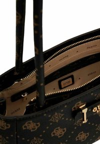 Sac à main en cuir noir avec motif logo doré, doté d'une fermeture éclair, d'une doublure intérieure beige et d'une étiquette intérieure. Deux poignées robustes.