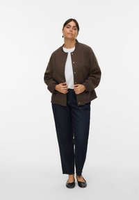 Veste bomber en mélange de laine marron avec un col rond et des boutons-pression, associée à un jean droit bleu foncé et des ballerines noires.