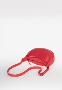 Borsa a spalla in pelle rossa con forma arrotondata, dotata di chiusura con zip e una tracolla piatta per il trasporto. Texture liscia e design minimalista.