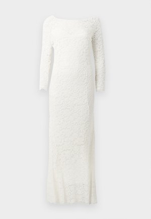 Robe en dentelle blanche à manches longues avec une silhouette ajustée, ornée de motifs floraux et d'un col bateau, se terminant au niveau de la cheville.