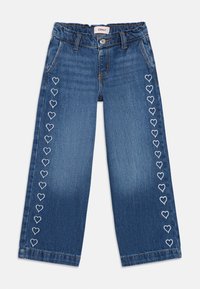 Τζιν παντελόνι με φαρδύ πόδι σε σκούρο μπλε με άνετη εφαρμογή. Διαθέτει λευκή κεντητή καρδιά κατά μήκος των πλαϊνών ραφών και ελαστική μέση με ρίγες.