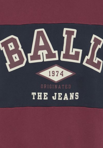 Maroon ja navy sweatshirt, millel on julged valged kirjad: "BALL 1974 ORIGINEERIS JEANSID" ning aasta all olev teemandikujuline aktsent.