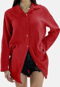 Rood overhemd met knopen, gemaakt van een gestructureerde stof, voorzien van een kraag, lange mouwen en zijzakken met een iets langere zoom.