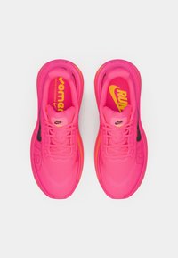 Φωτεινά ροζ αθλητικά παπούτσια Nike για τρέξιμο με κορδόνια και μαξιλαρωτές σόλες, απεικονισμένα από πάνω σε λευκό φόντο.