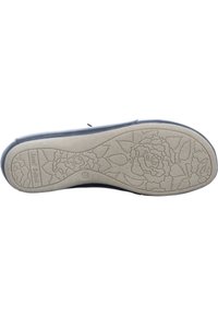 Semelle de chaussure bleu foncé avec une surface en caoutchouc beige texturé ornée de motifs floraux. Branding imprimé visible près du talon.