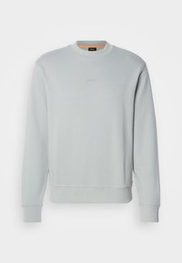 Sweat-shirt gris clair à col rond, manches longues, avec un logo embossé subtil centré sur la poitrine.