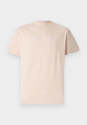 Lichtroze katoenen t-shirt met een geborduurd "GUESS" logo en "EST. 1981" detail op de voorkant, met een klassieke ronde hals en korte mouwen.