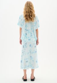 Ljusblått tie-dye topp med korta ärmar, elastisk midja och matchande kjol. Mjukt tyg med en flödande design och ankellång fåll.
