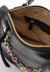Borsa in pelle nera con zip dorata, interno caratterizzato da un motivo logo e un accento di catena colorata sul lato esterno.