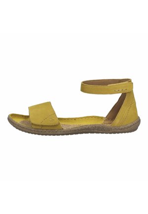 Sandale en daim jaune avec une semelle plate, un bout ouvert, une bride de cheville et une semelle extérieure en caoutchouc texturé. Elle dispose d'une semelle intérieure rembourrée pour le confort.