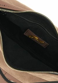 Borsa a mano di color marrone chiaro con chiusura a zip, materiale esterno morbido e interno in tessuto nero. Presenta dettagli in zip dorati e un'etichetta in pelle.