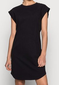 Robe t-shirt en coton noir avec un col rond, des manches courtes et une coupe décontractée. Design simple, longueur genoux, texture lisse, sans motifs.