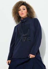 Marinblå långärmad sweatshirt med hög krage, med grafisk design och strassdetaljer. Slät tygkvalitet och avslappnad passform.