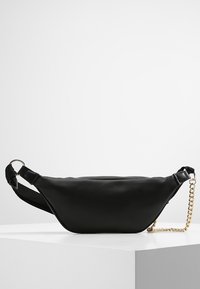Marsupio in pelle nera con un design elegante e curvo. Presenta una tracolla in metallo dorato staccabile e una cintura in tessuto nero regolabile.