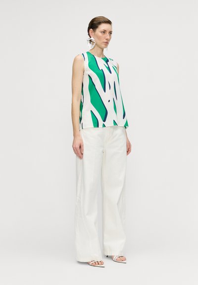 Top sin mangas elegante con base blanca que presenta patrones abstractos en verde y azul, combinado con pantalones blancos holgados y sandalias con tiras.