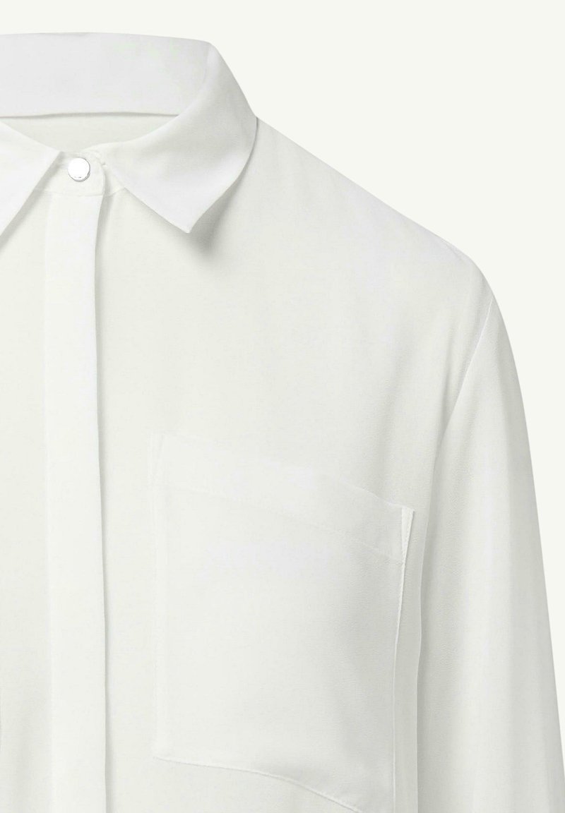 Weiße Bluse mit klassischem Kragen, durchgehender Knopfleiste und einer Brusttasche. Glatte Textur, leichtes Material und elegantes Design.