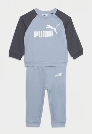 Jasnoniebieski i ciemnoszary dres dla małego dziecka z logo Puma na piersi i lewej nogawce, długie rękawy i zatrzaski na ramieniu.