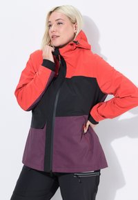 Giacca impermeabile rossa, nera e viola con cappuccio, chiusura con zip e molteplici tasche. Presenta un design a blocchi di colore e polsini elasticizzati.