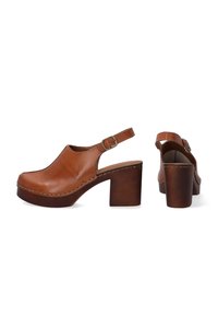 Braune Leder-Slingback-Clogs mit runder Zehe, dickem Absatz, kontrastierender Naht und verstellbarem Schnallenverschluss.