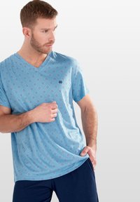 Felpa da uomo a maniche corte con scollo a V di colore azzurro chiaro, decorata con un motivo geometrico. Realizzata in un tessuto morbido, presenta un logo discreto sul petto.