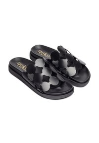 Sandales noires à talon plat avec un motif floral découpé sur la sangle, un lit de pied texturé et une semelle plate pour le confort.