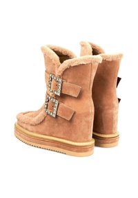 Botas de tobillo de ante color canela con forro de piel sintética, que cuentan con dos hebillas decorativas con acentos de rhinestone y una suela de goma texturizada.
