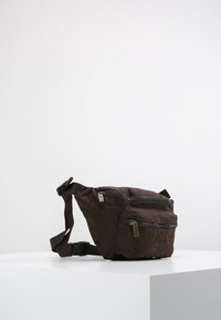 Brown fabric fanny pack with two zippered compartments, adjustable strap, and a textured surface. Compact, practical design with a minimalist look.