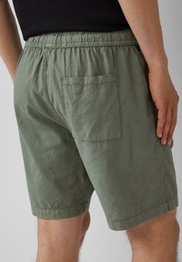 Groene katoenen shorts met een elastische tailleband, één achterzak en een relaxte pasvorm. Soepele textuur en lengte boven de knie.