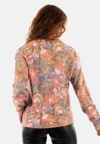 Pull en tricot avec un motif floral pastel ; présente des manches longues, un col rond et une coupe décontractée ; confectionné en tissu doux et texturé.