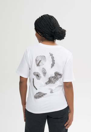Vrouw met gevlochten haar die een wit T-shirt draagt met zwart-witte abstracte illustraties van zeedieren op de achterkant.