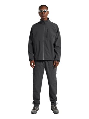 Mand iført mørkegrå lynlåstrøje, cargobukser, vandresko og solbriller, stående med fronten mod kameraet på hvid baggrund.