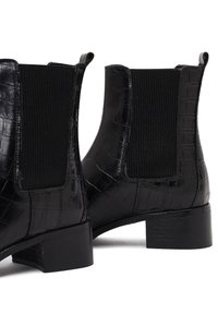 Botas negras de cuero hasta el tobillo con textura de cocodrilo, paneles laterales elásticos y un tacón bajo en bloque. Diseño simple y elegante para un uso versátil.