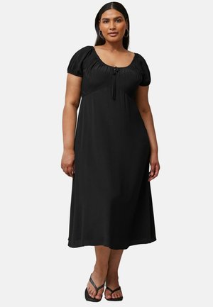 Zwarte midi-jurk met korte poffende mouwen, ronde halslijn en strikdetail aan de voorkant. Gemaakt van zacht materiaal met een relaxte pasvorm.