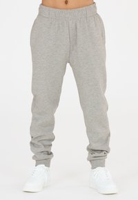 Hellgraue Jogginghosen mit einem elastischen Bund, Bündchen an den Knöcheln und einer weichen Textur. Kombiniert mit weißen Sneakers.